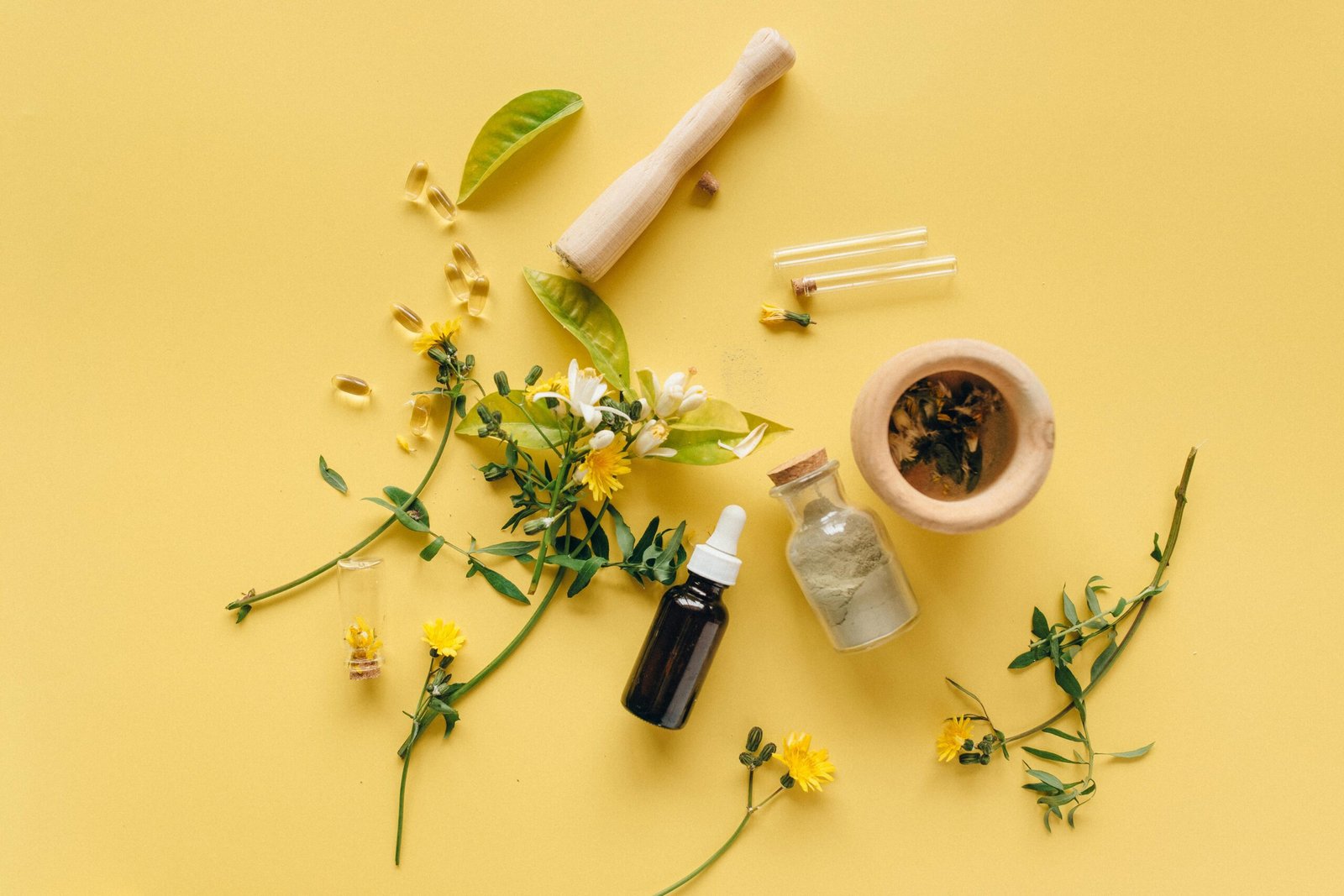 A flat lay of herbal medicines and plants on a yellow background for natural healing.