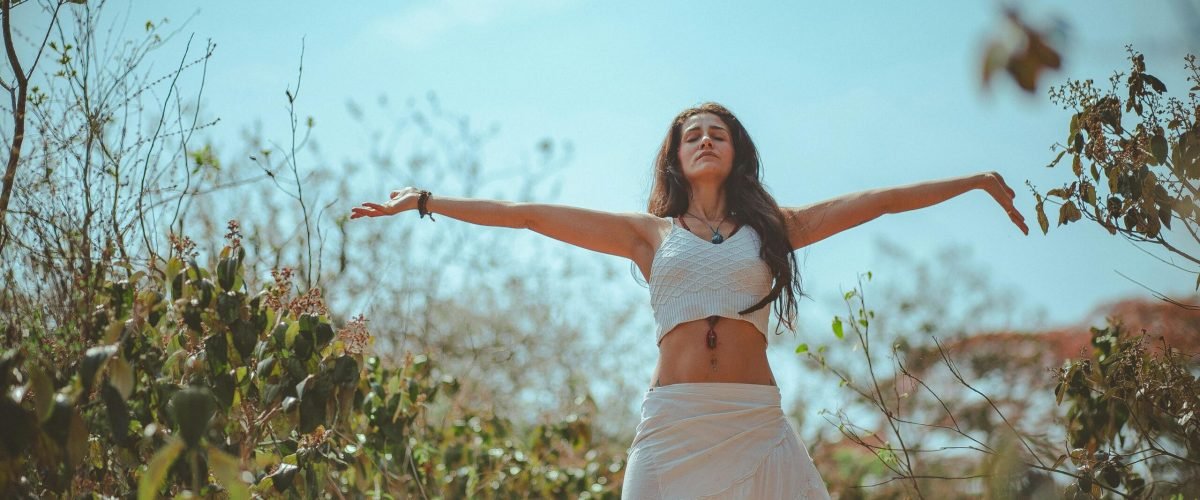 Peaceful scene of a woman meditating outdoors in a sunny summer setting, embodying wellness and tranquility.