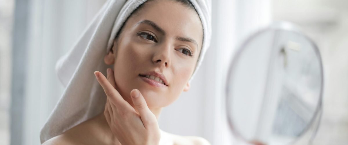 A serene and elegant woman enjoys a skincare ritual, enhancing her natural beauty in the comfort of her home.