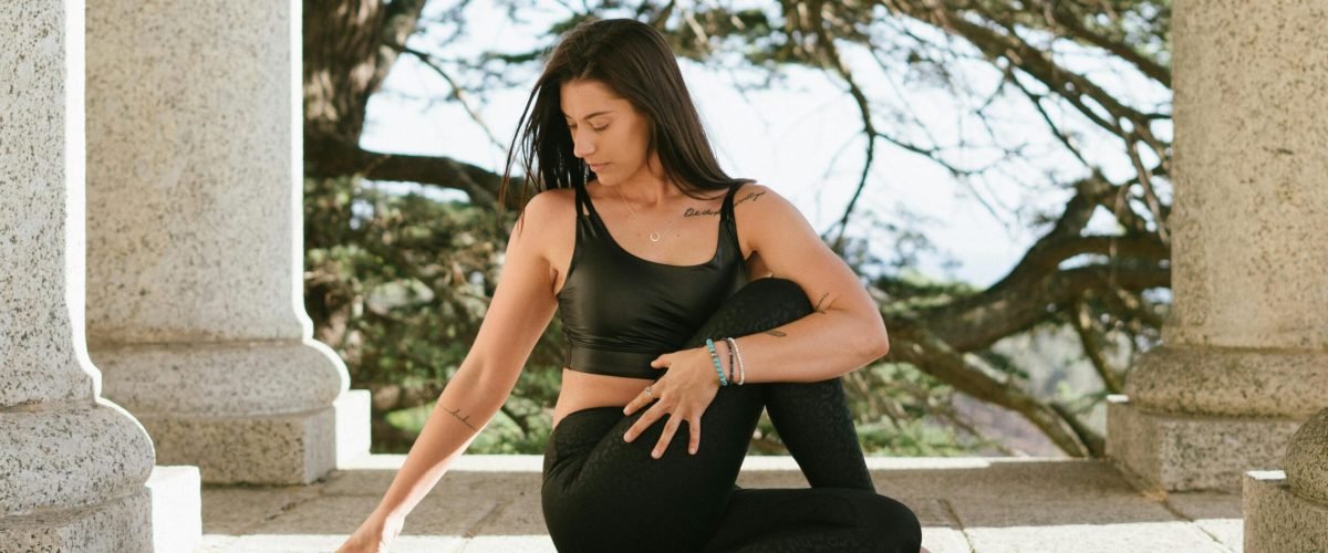 Woman practicing yoga outdoors, conveying tranquility and mindfulness amidst stone columns.