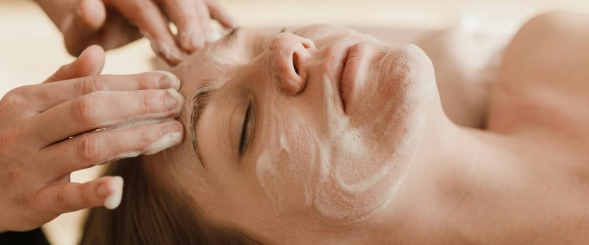 A close-up of a woman receiving a soothing facial massage with a skincare mask.